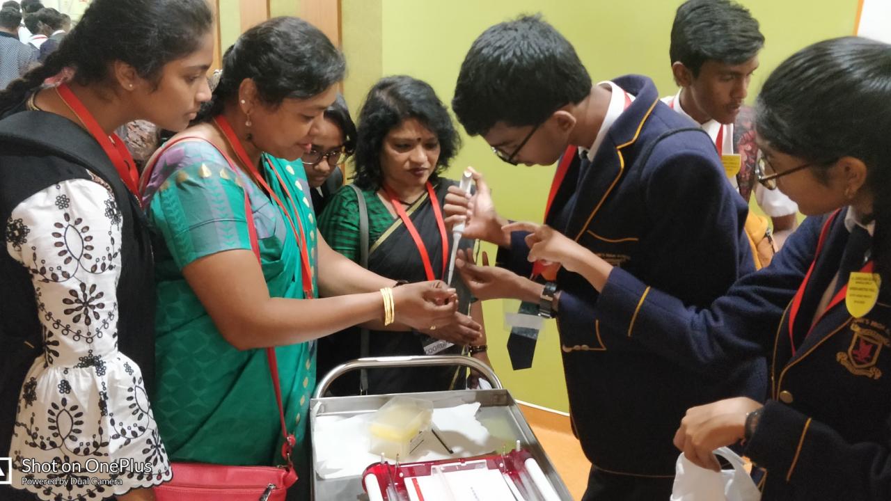 Group of students and teachers examining an object in a classroom setting.