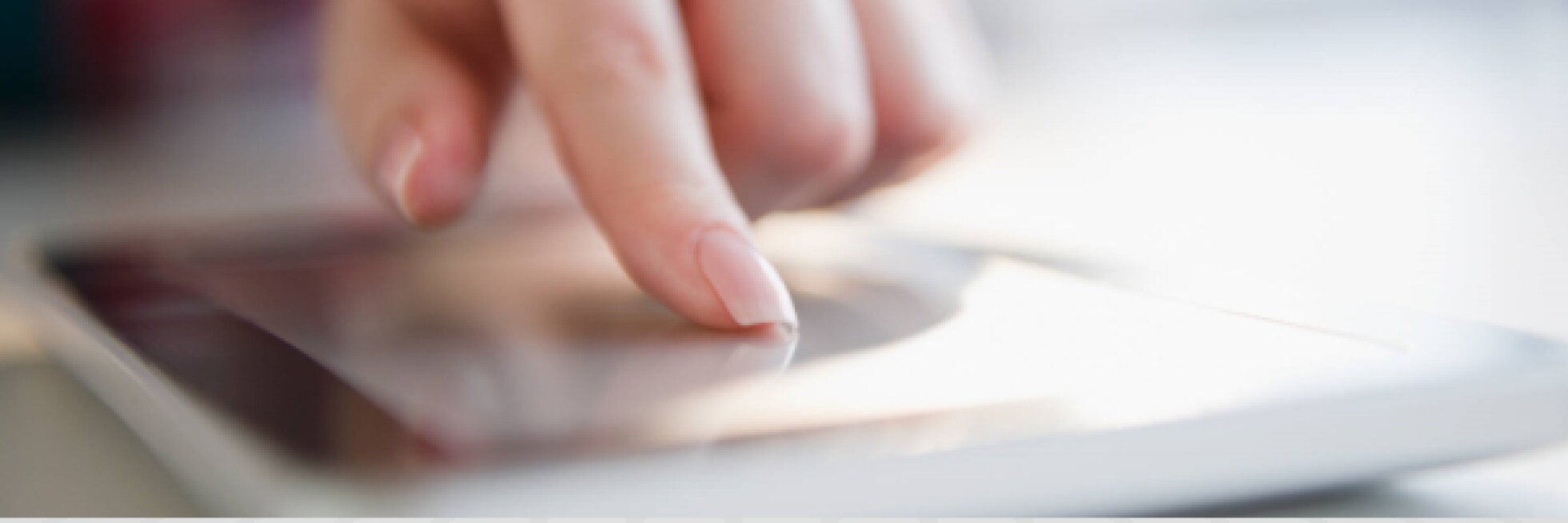 A person's finger touches a glowing tablet screen, interacting with the device.