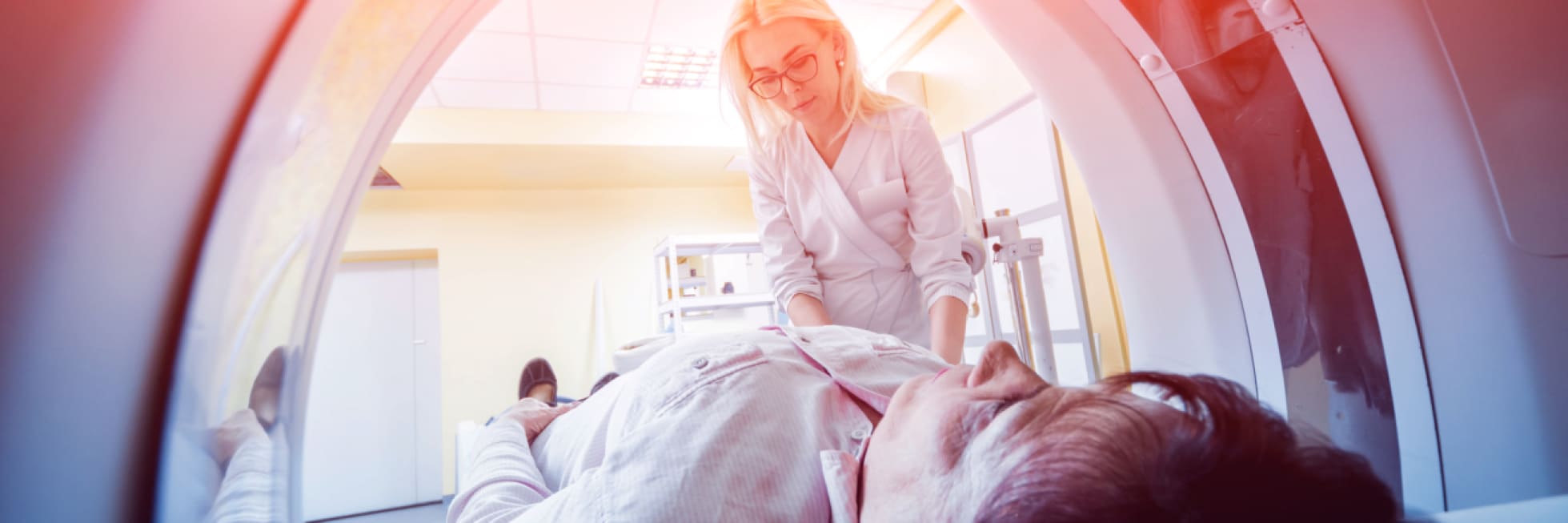 A medical professional assists a patient entering an MRI scanner in a clinical setting.