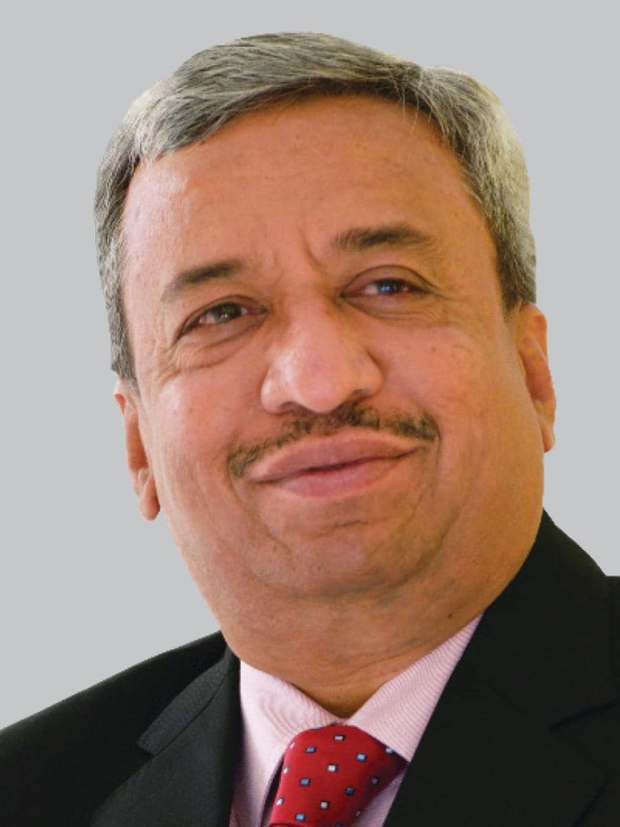 Man with gray hair and mustache wearing a suit and red tie, looking off to the side with a neutral expression.